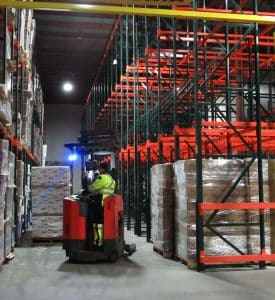 Forklift operator in thermal gear navigating through Steel King heavy-duty cold storage drive-in pallet racks.