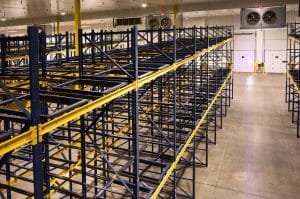 High-angle view of empty blue and yellow dynamic Steel King pallet racks in a refrigerated warehouse.